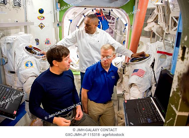 NASA astronauts Michael Barratt (left), Alvin Drew (background) and Tim Kopra, all STS-133 mission specialists, participate in a training session in an...