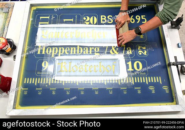 23 June 2021, Saxony, Penig: At Muldenthaler Emallierwerk GmbH, the head of the sign department, Katrin Engert-Hecht produces signs using the hand screen...