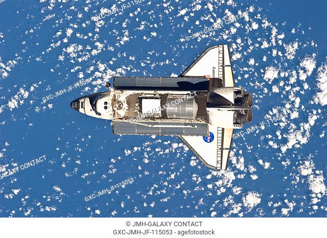 Backdropped by a blue and white part of Earth, space shuttle Discovery is featured in this image photographed by an Expedition 26 crew member as the shuttle...