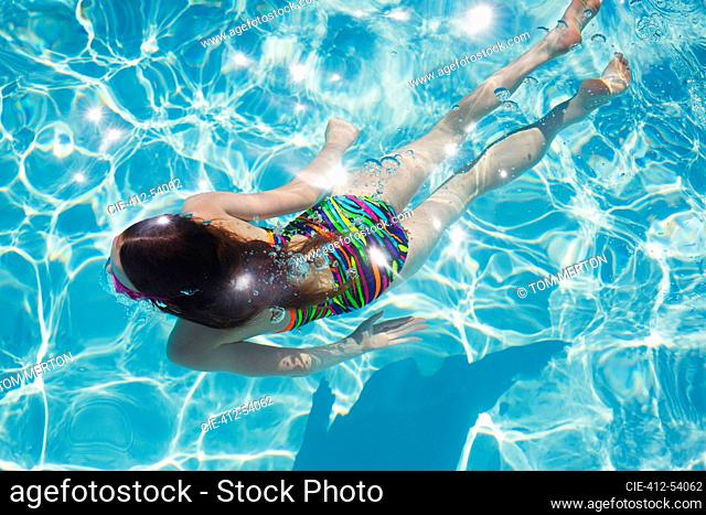 Girl swimming in sunny summer swimming pool