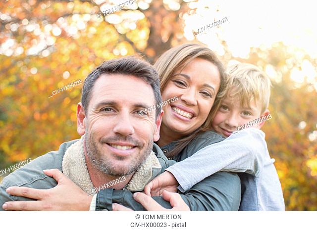 Portrait smiling family hugging in front of autumn leaves