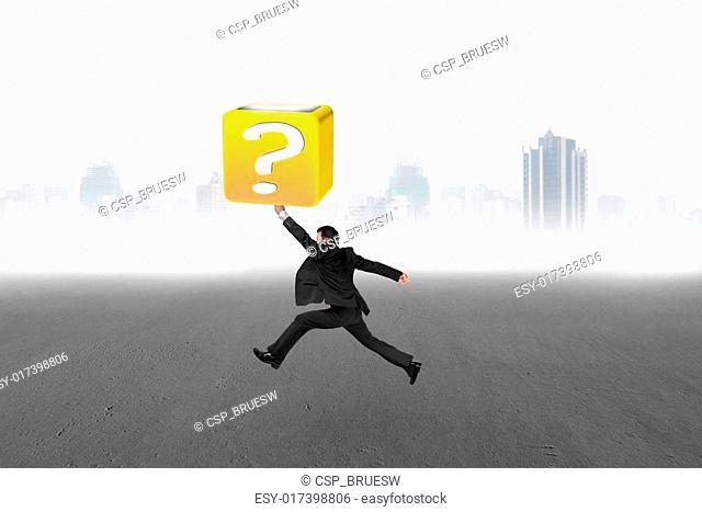 Jumping businessman hitting 3d question mark box with cityscape
