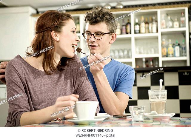 Germany, Bavaria, Munich, Young man feeding piece of cake to woman in cake