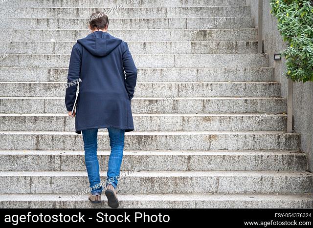 Young man Holding Computer Laptop Walking Up Stairs outdoor