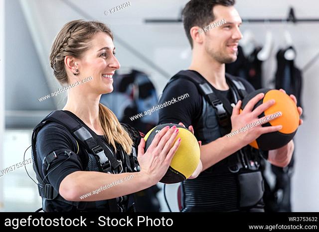 Fit and beautiful woman and man with ball in wireless ems exercise gym