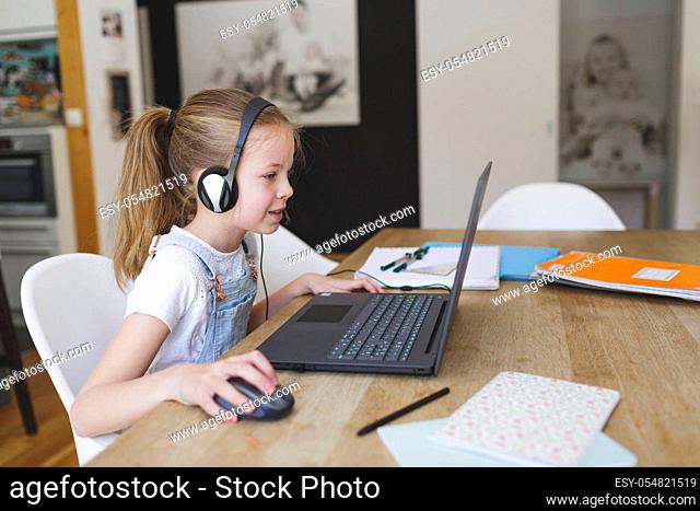 beautiful young girl with headset is sitting in front of her laptop during corona time