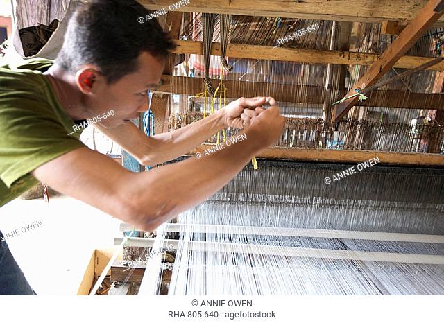 Silk weaver working to resolve a problem with a broken thread on a traditional wooden loom in a factory in Pekalongan, Java, Indonesia, Southeast Asia, Asia