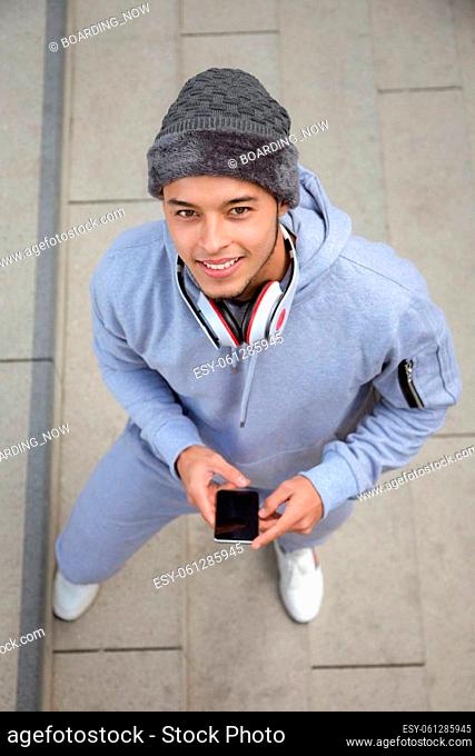 Listening to music smiling young latin man runner portrait format sports training from above outdoor