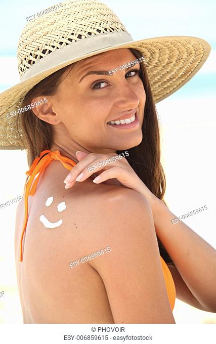 woman with sunscreen on the beach wearing a hat