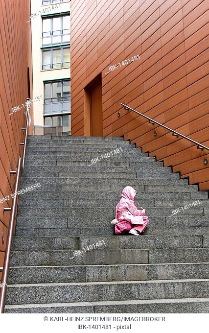 Toddler sitting alone and abandoned on the steps of a housing complex