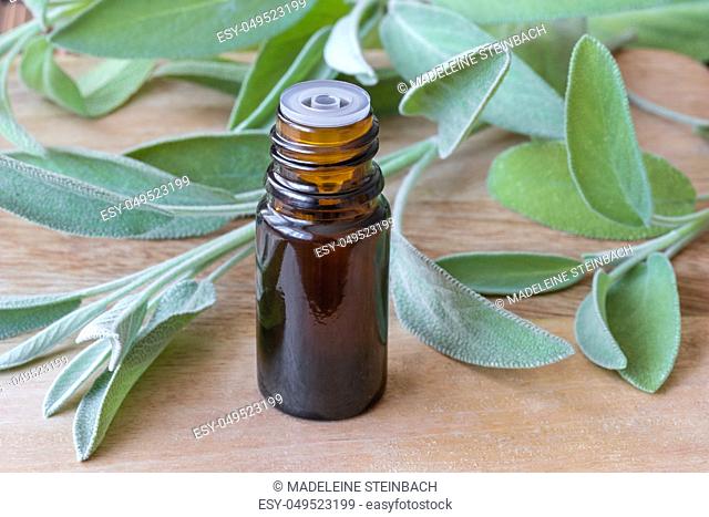 A bottle of essential oil with fresh sage twigs