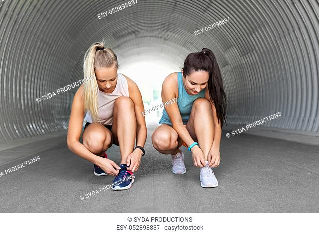 sporty women or female friends tying shoe laces