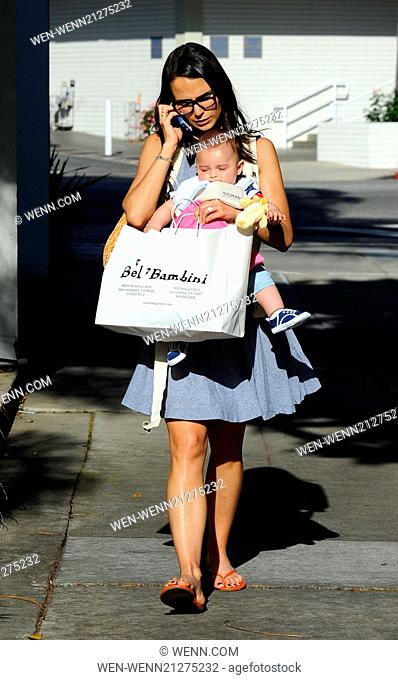 Jordana Brewster out and about talking on her cell phone as she has a handful multi-tasking carrying her son Julian in a sling and a shopping bag of toys from...