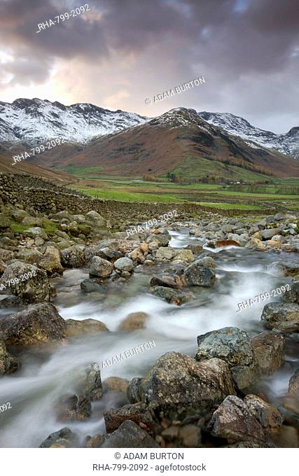 Redacre Gill river tumbling over rocks towards the snow capped mountains surrounding Great Langdale, Lake District National Park, Cumbria, England