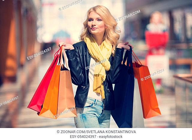 Sale and people - smiling woman with colorful shopping bags over supermarket background