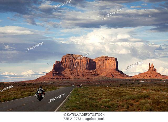 Motorcycle driving towards buttes in Monument Valley, Utah, USA