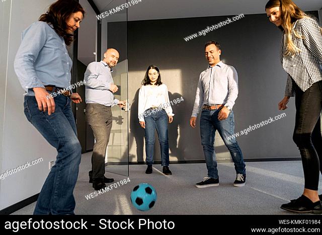 Business colleagues playing soccer in office