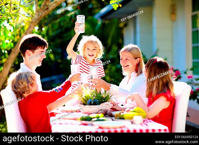 Family eating outdoors. Garden summer fun. Barbecue in sunny backyard. Grandmother and kids eat lunch in outdoor deck. Parents and children enjoy bbq