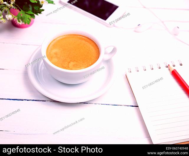 A cup of coffee and an empty paper notebook with a red pencil