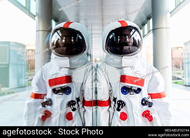 Male astronaut leaning on glass wall
