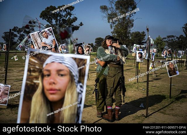 01 December 2023, Israel, Re'im: Israeli soldiers mourn next to the images of the killed Israelis at the site of the Re'im music festival massacre