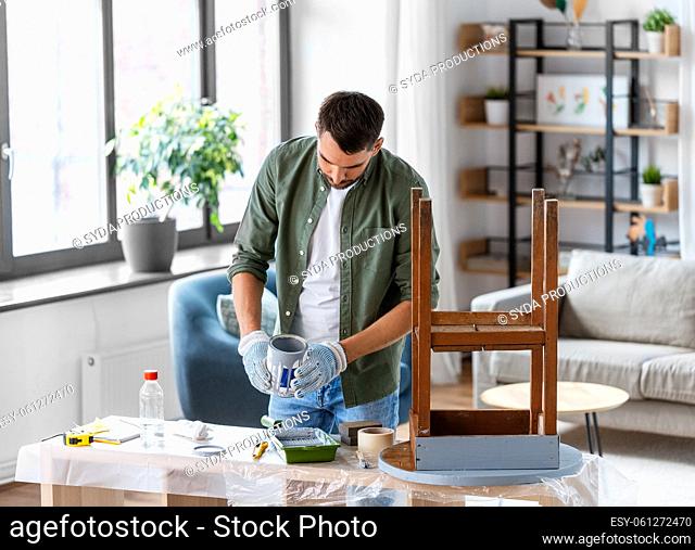man in gloves pouring grey color paint to tray