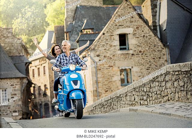 Carefree Caucasian couple riding blue motor scooter