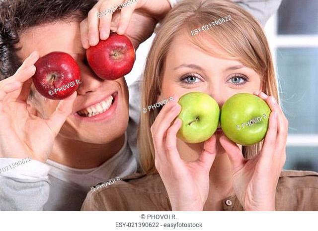 Funny couple covering their eyes with apples