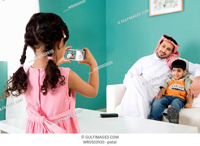 Daughter taking photos of her father and brother in the living room