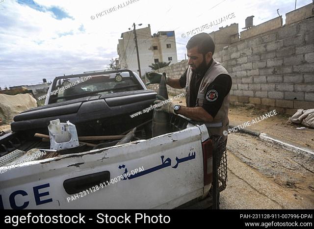 28 November 2023, Palestinian Territories, Khan Yunis: A member of Hamas Police Explosives Control team loads unexploded shells in a police vehicle during the...