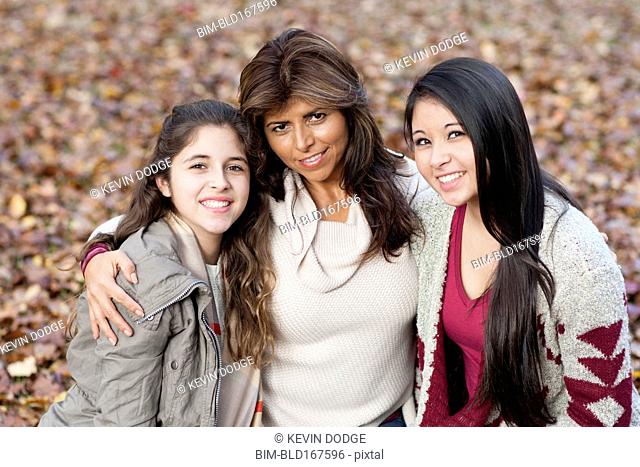 Hispanic mother and daughters hugging outdoors