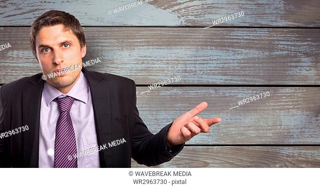 Portrait of businessman shrugging shoulders against wooden wall