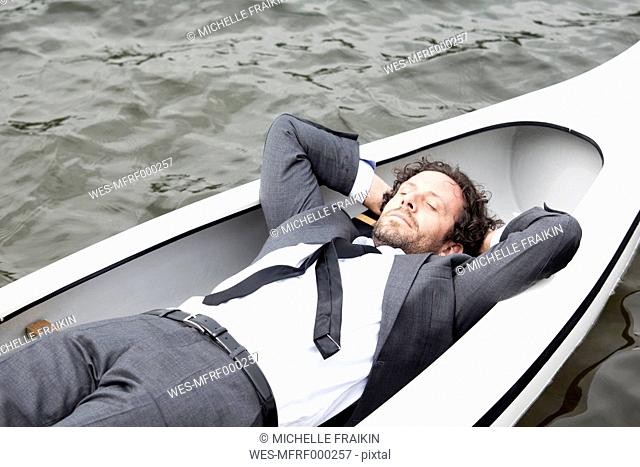 Germany, Rur Reservoir, businessman sleeping in canoe