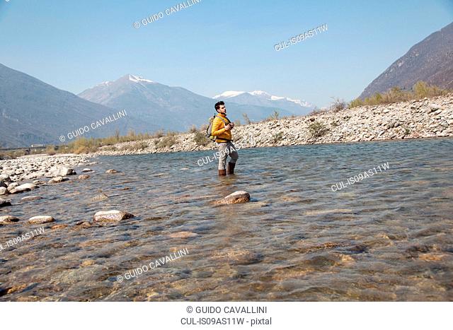 Young male hiker looking out from Toce river, Vogogna, Verbania, Piemonte, Italy