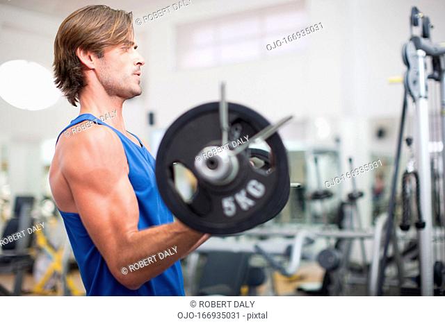 Man lifting barbell in gymnasium