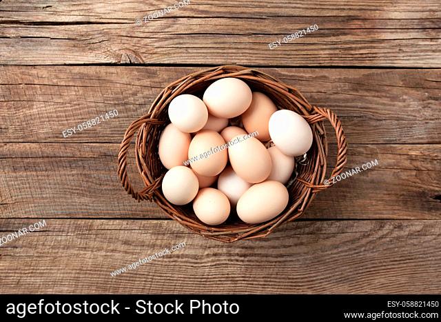 Organic chicken eggs in basket on wooden background. Organic household concept with eggs from free-range and pasture raised hens