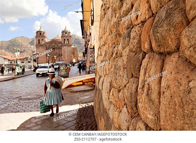 Ancient Inca walls and a Quechua woman with traditional dress in the city center, Cusco, Peru, South America