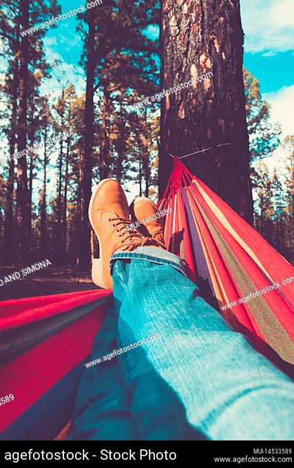 Legs and hammock relax leisure activity with forest woods and sky in background - people enjoy environment and alternative free lifestyle enjoying nature and...