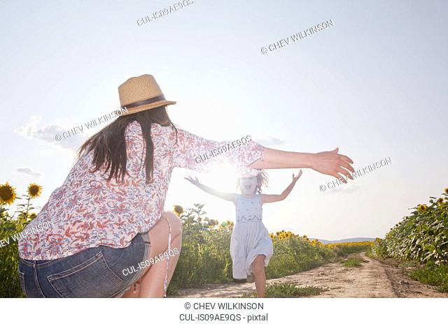 Girl running through field to mother with open arms