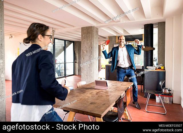 Smiling businesswoman showing winning gesture while playing with woman at office