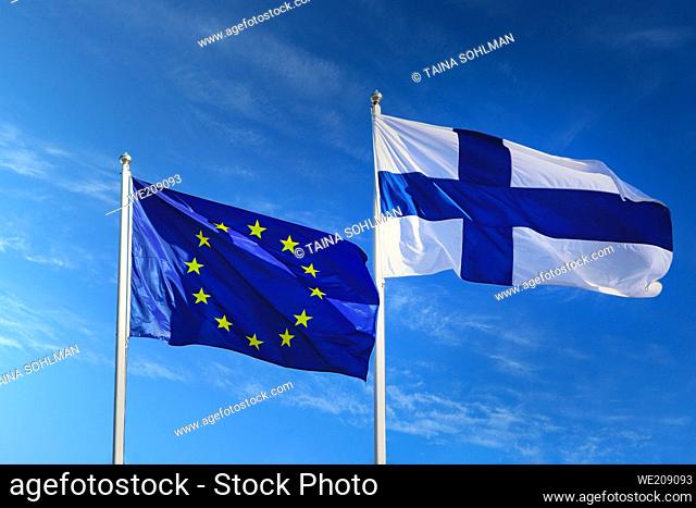 Flags of EU and Finland against blue sky with white clouds on Europe Day May 9, 2020