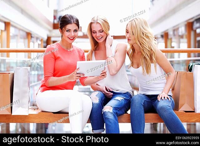 Young beautiful happy women with tablet pc and shopping bags in mall