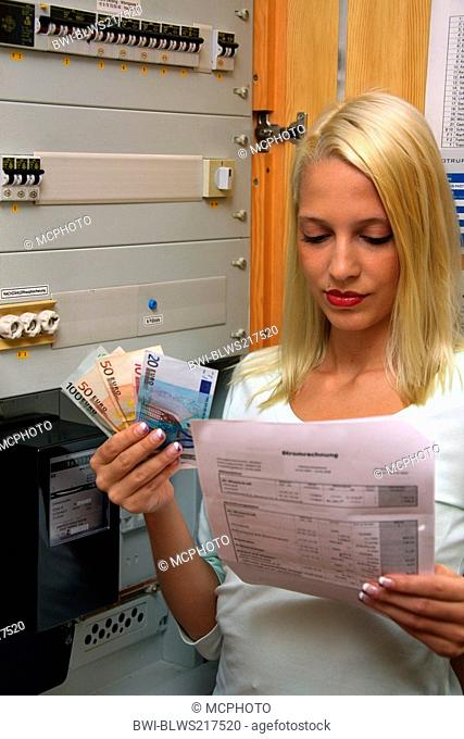 young blond woman with bill and money at the meter box