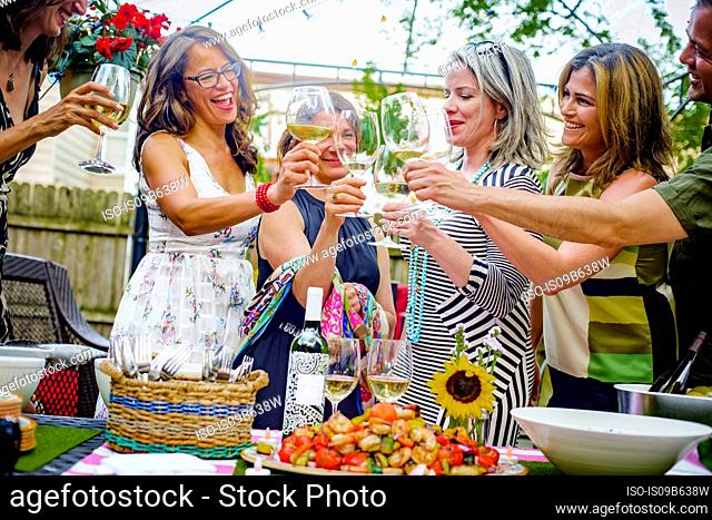 Group of people at garden party, holding wine glasses, making a toast