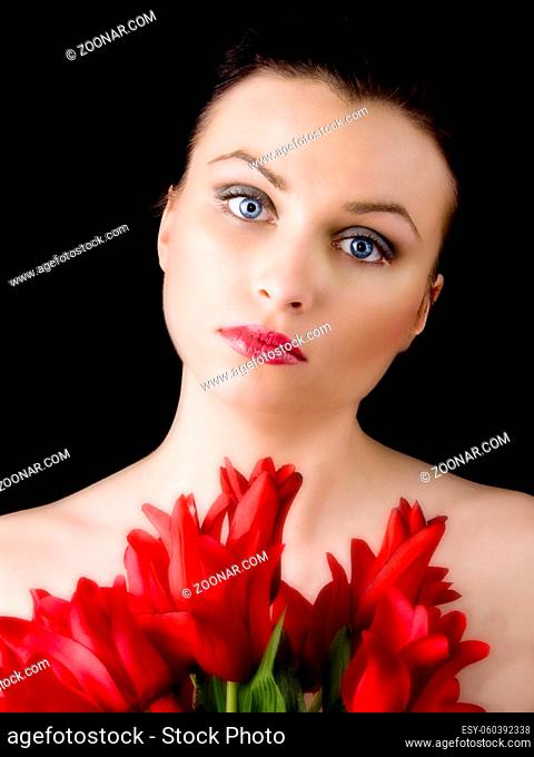 Portrait of young beautiful woman with red tulips on black background