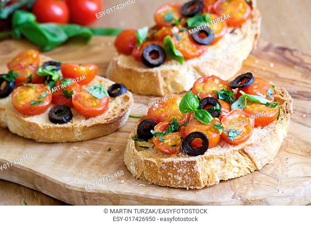 Toasted bread topped with cherry tomatoes, black olives and basil