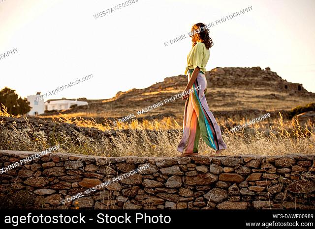 Beautiful woman taking a walk at sunset, Mykonos, Greece
