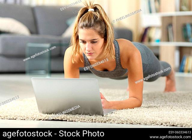 Full body portrait of a woman practicing sport watching video tutorials on laptop at home