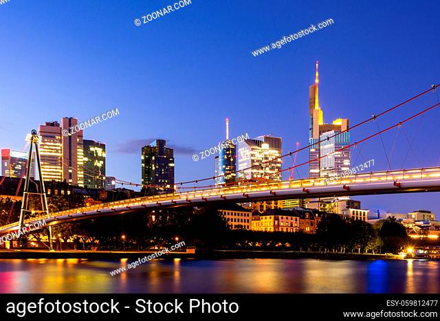 The Holbeinsteg footbridge in Frankfurt acrross Main river with view to the skyline at night