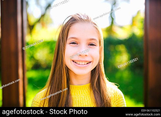 Portrait of modern happy teen girl with dental braces dressed in yellow clothes in park. Pretty teenage girl wearing braces smiling cheerfully
